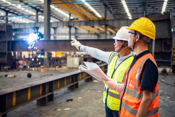 Photo of 2 workers wearing personal safety gear at a steel production facility