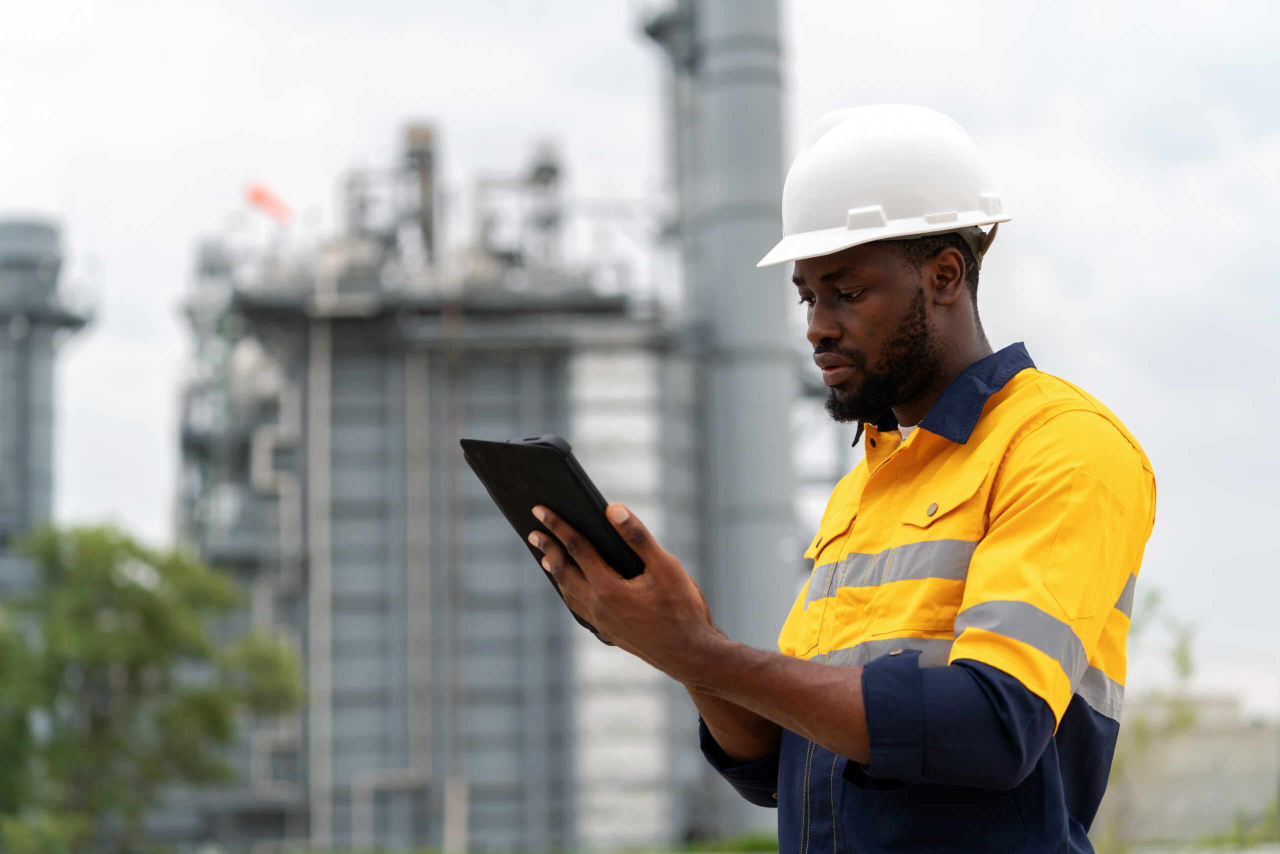 Photo of an engineer looking at a tablet in front of a plant
